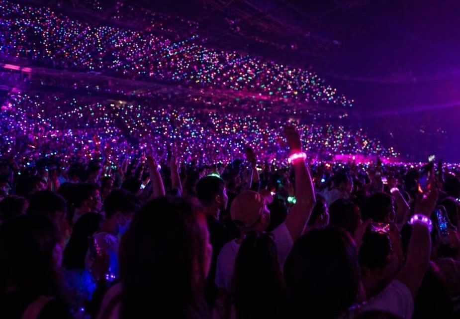Hundreds of LED concert bands pulsing uniformly in dynamic sync at a live technology demonstration booth