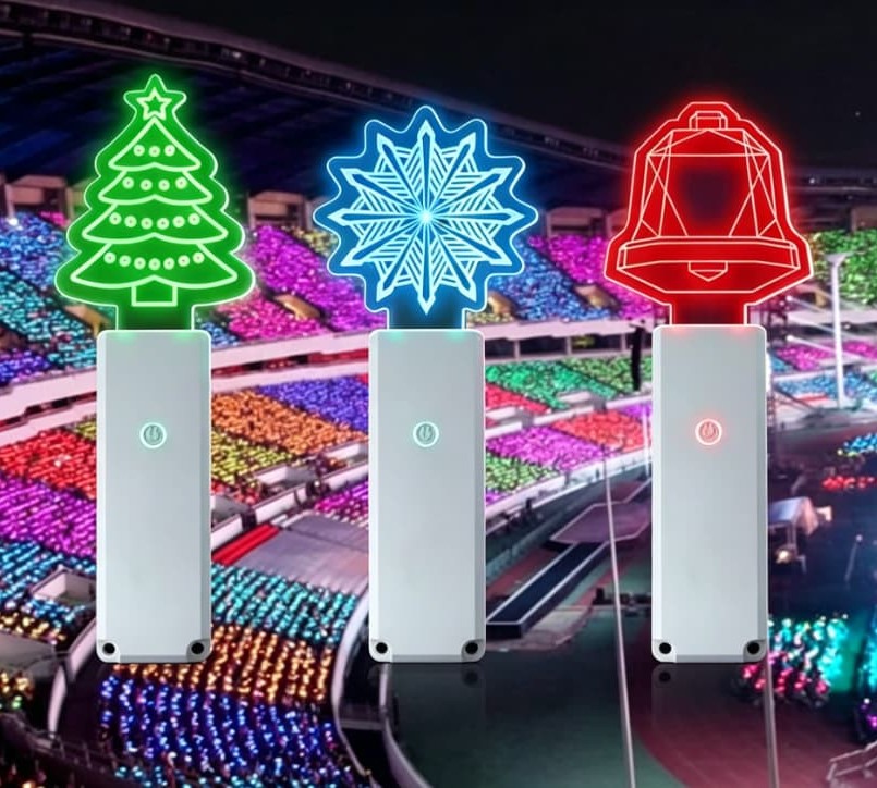 Massive concert stadium backdrop showing thousands of glowing light sticks controlled in perfect sync by a central wireless radio setup