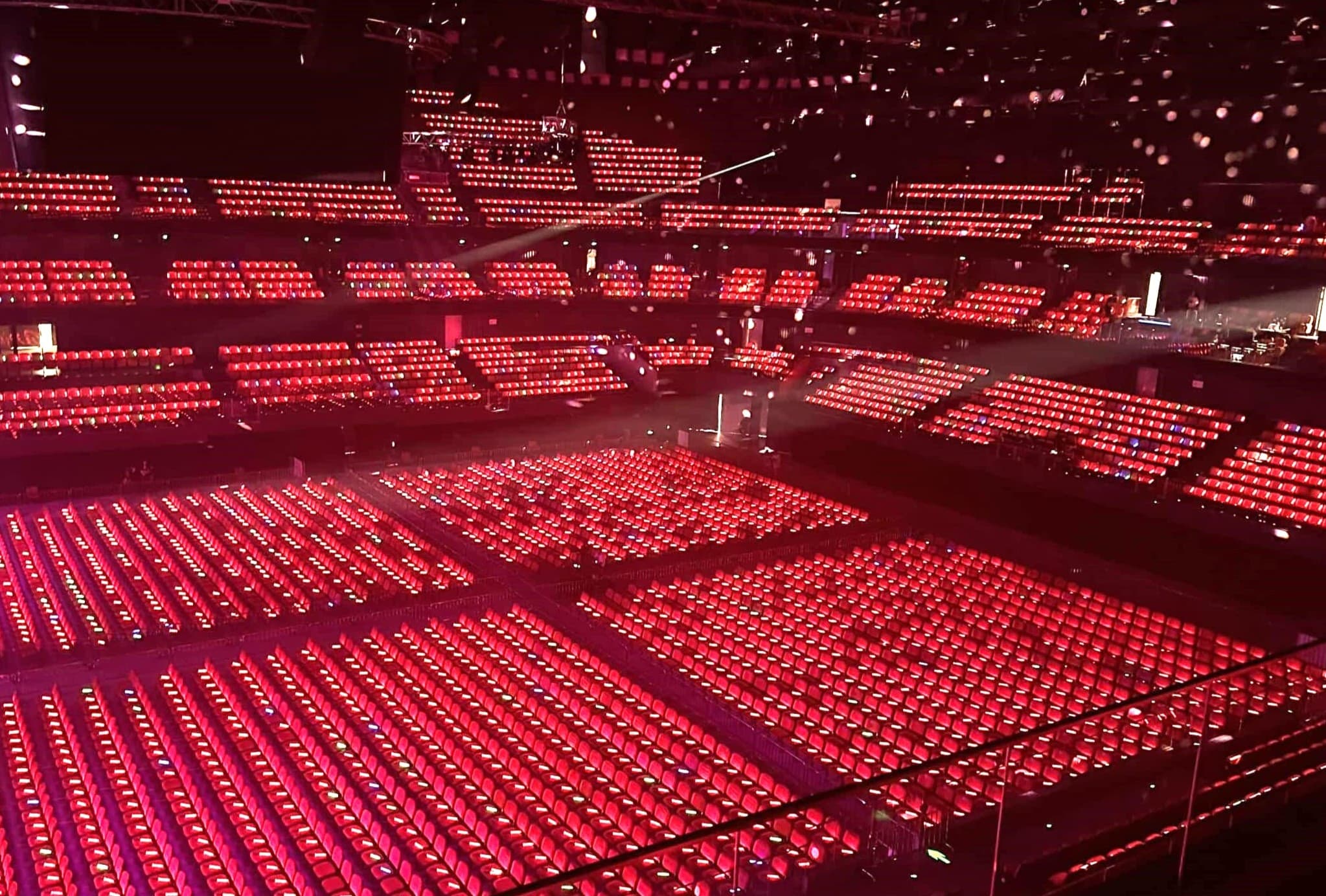 Audience wave of synchronized LED lanyard colors sweeping across stadium seating