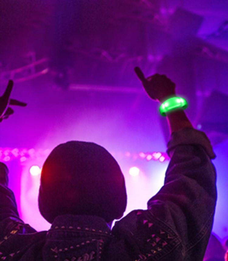 Thousands of synchronized custom LED bracelets blinking at a massive live arena concert stadium
