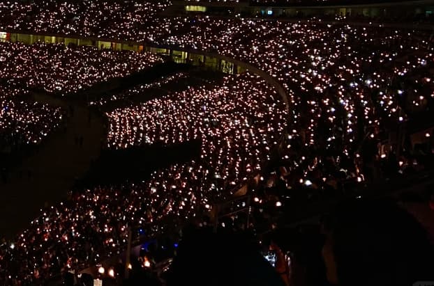Light stick concert at Seoul Olympic Stadium with synchronised audience light sticks creating coordinated colour waves
