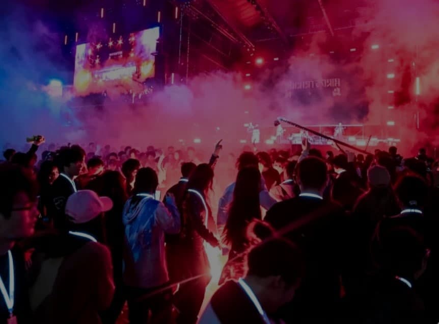 Concert crowd with synchronized light up lanyards creating an audience light display